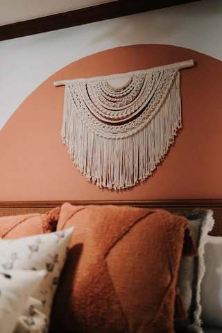 a close up of a bed with pillows and a wall hanging