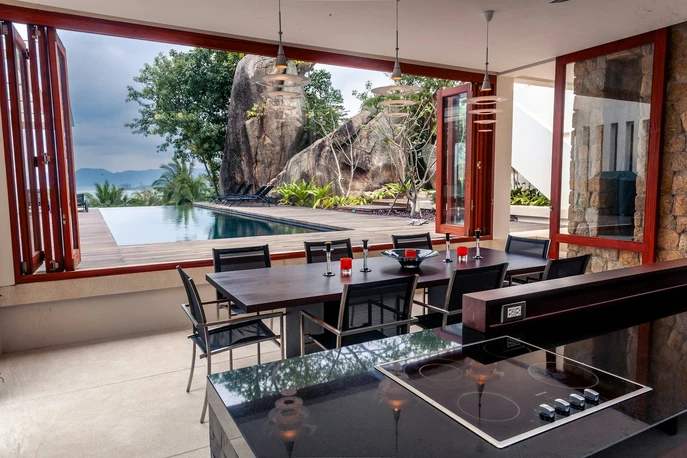 Modern dining area with a view of the pool and rocky landscape
